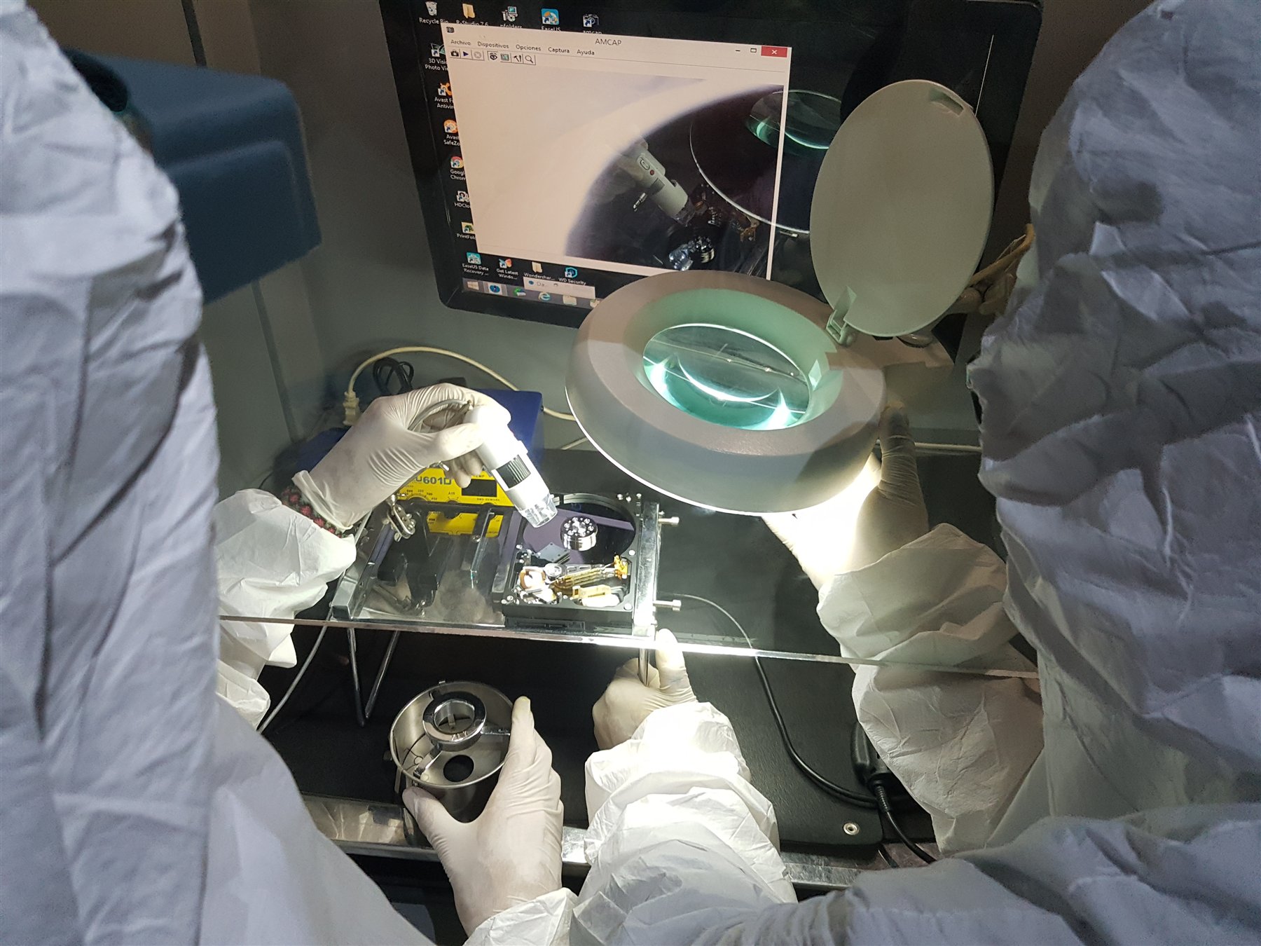 Fotografía de archivo de técnicos inspeccionando un disco duro abierto